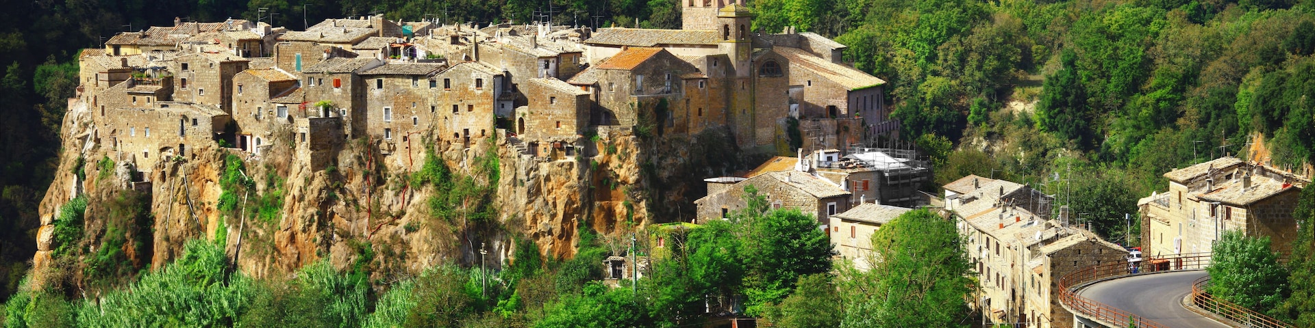 Un pueblo histórico fortificado enclavado en un acantilado, rodeado de exuberante vegetación.
