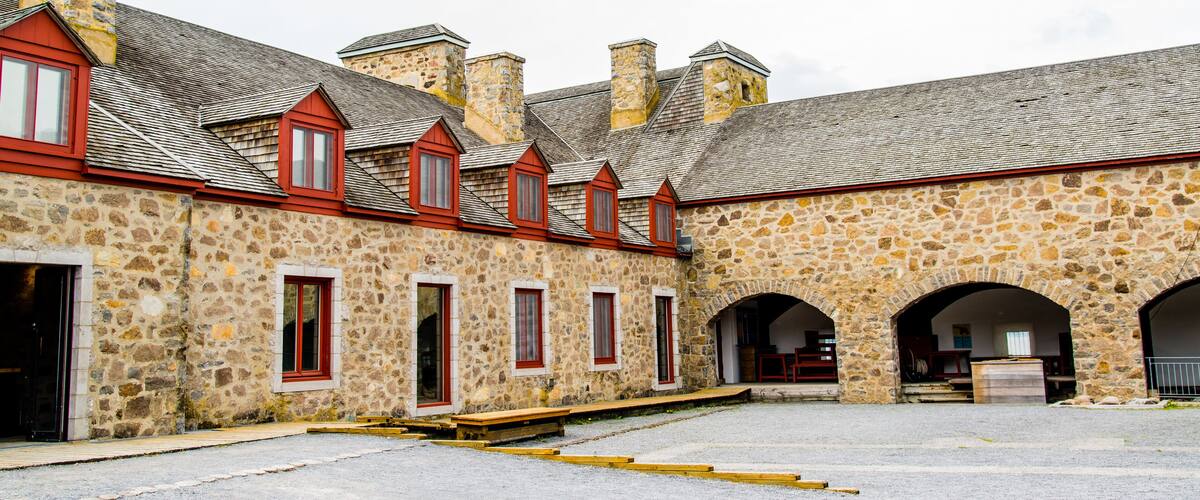 A stone building with red window frames and a tiled roof.