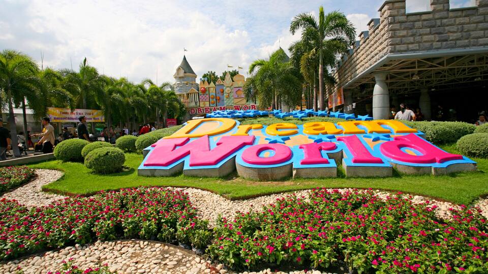 A sign for Dream World with colorful letters, surrounded by well-maintained gardens and palm trees.