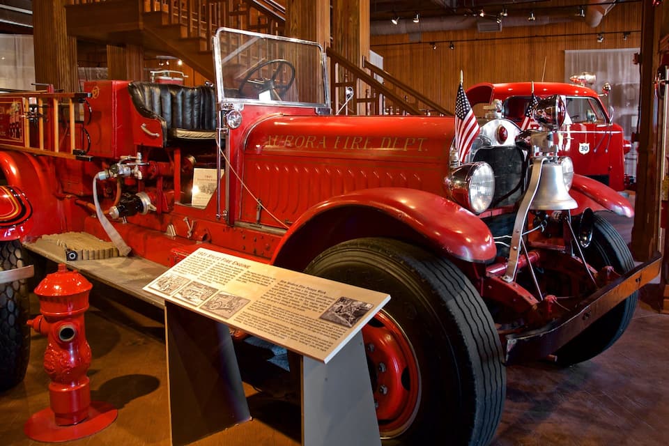 A vintage fire truck with a plaque, a red fire hydrant, and wooden interior.