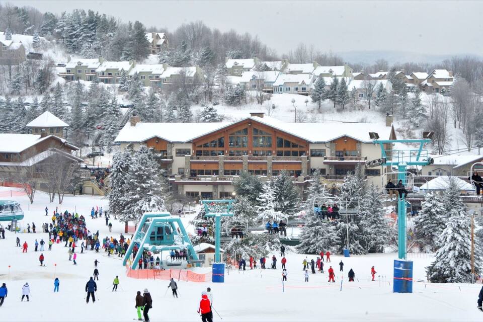 A snowy ski resort with a large lodge, ski lifts, and skiers.