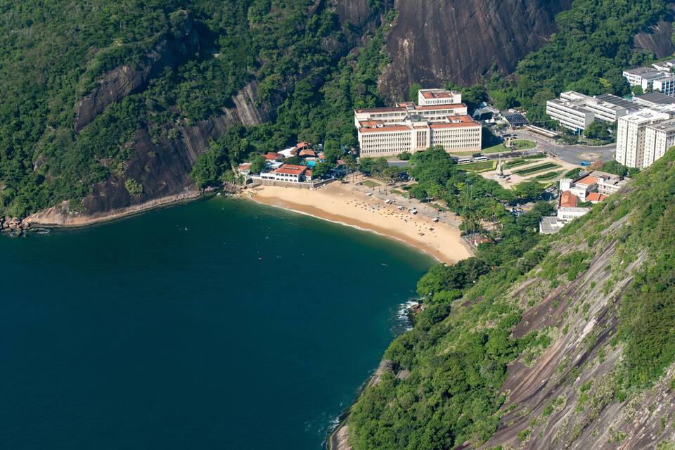 A coastal town with a beach, buildings, and a mountainous backdrop.
