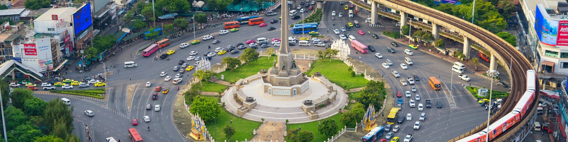 Aerial view of Victory Monument on busy street road. Roundabout in Bangkok Downtown Skyline. Thailand. Financial district center in smart urban city. Skyscrapers at sunset.