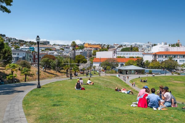 Mission Dolores Park showing picnicing and a park as well as a small group of people