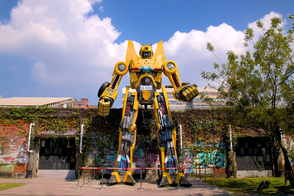 Een groot, geel robotbeeld voor een gebouw vol graffiti.