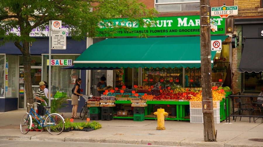 A fruit market with a green awning, a bicycle, and a sale sign.