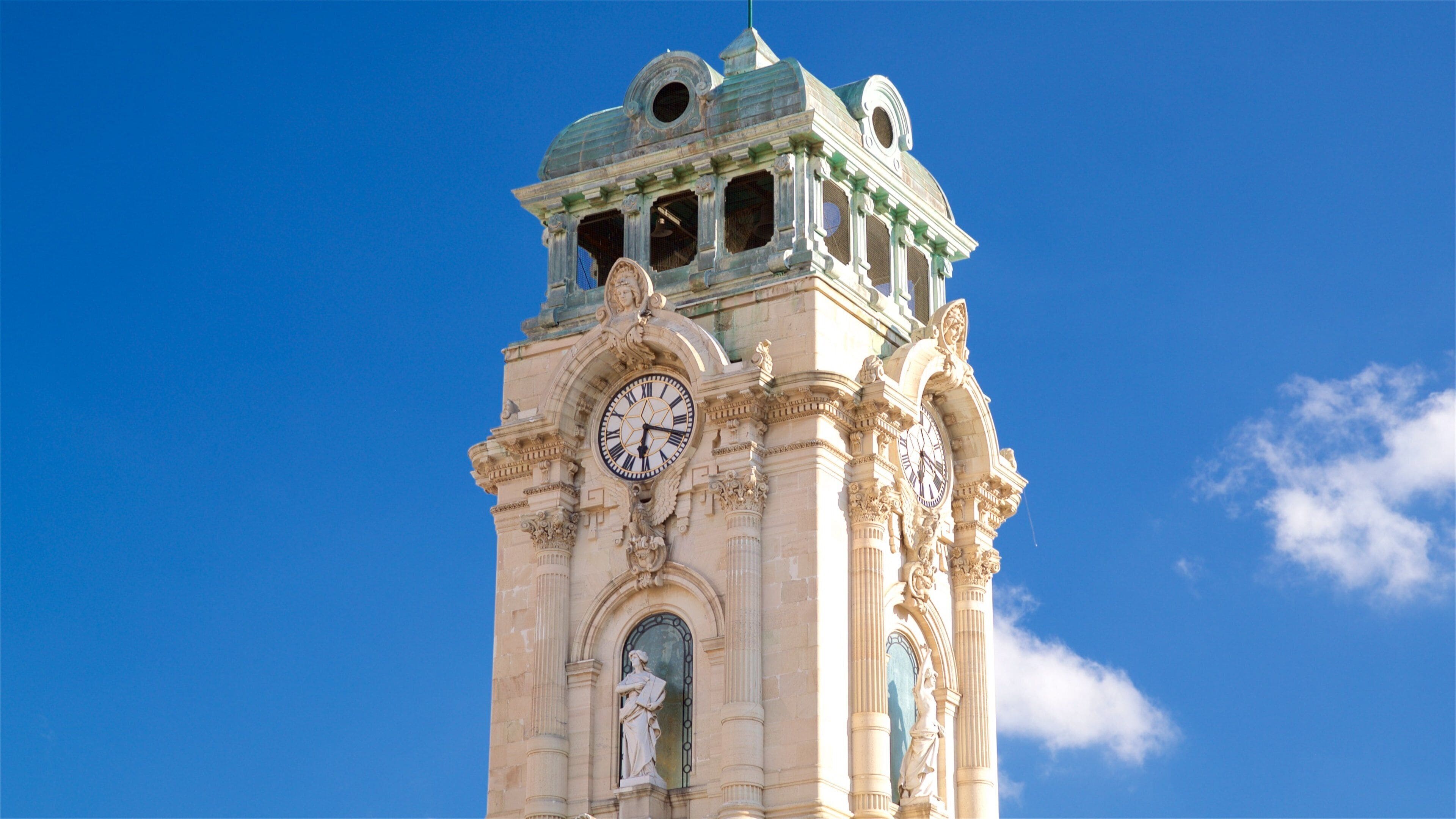 A clock tower with ornate sculptures and a clear blue sky.