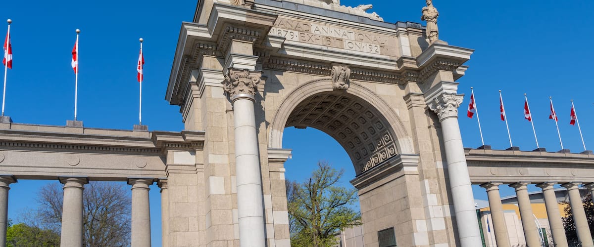 A grand archway with a statue on top, flanked by columns and flags.