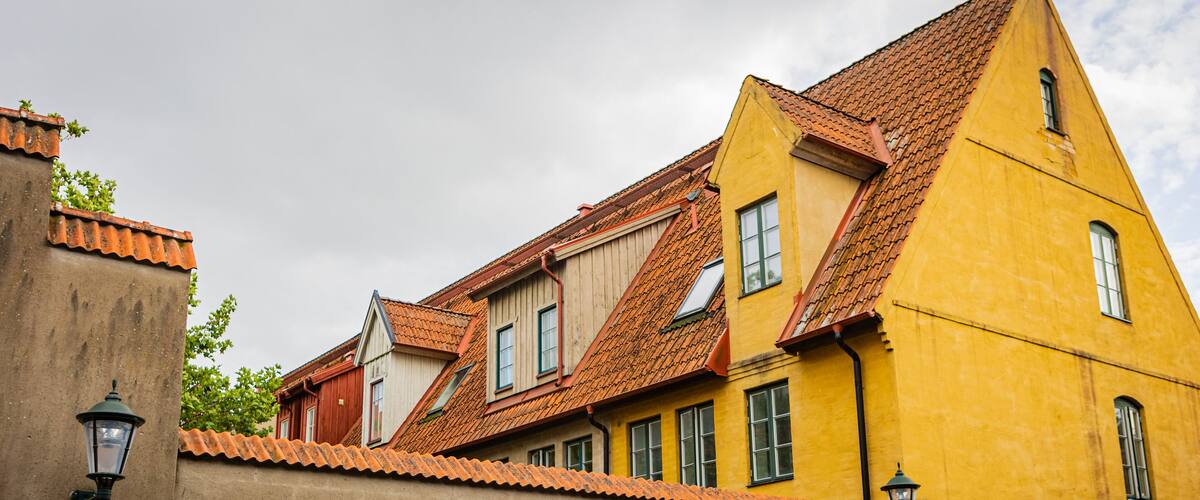 A yellow building with a red-tiled roof and a brown wall.