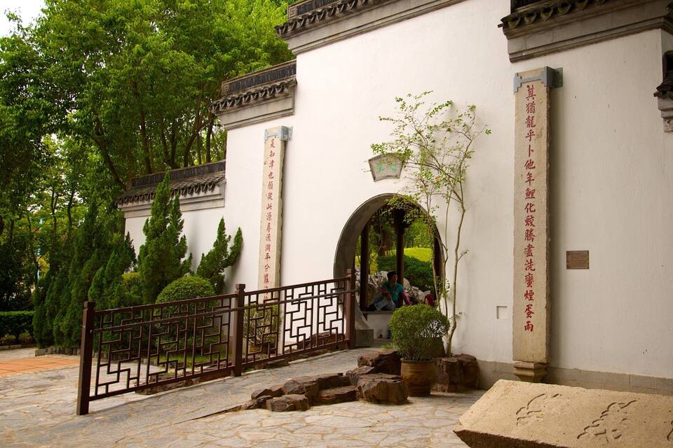 Een traditionele Chinese binnenplaats met stenen paden, een houten poort en een stenen plaquette met inscripties.