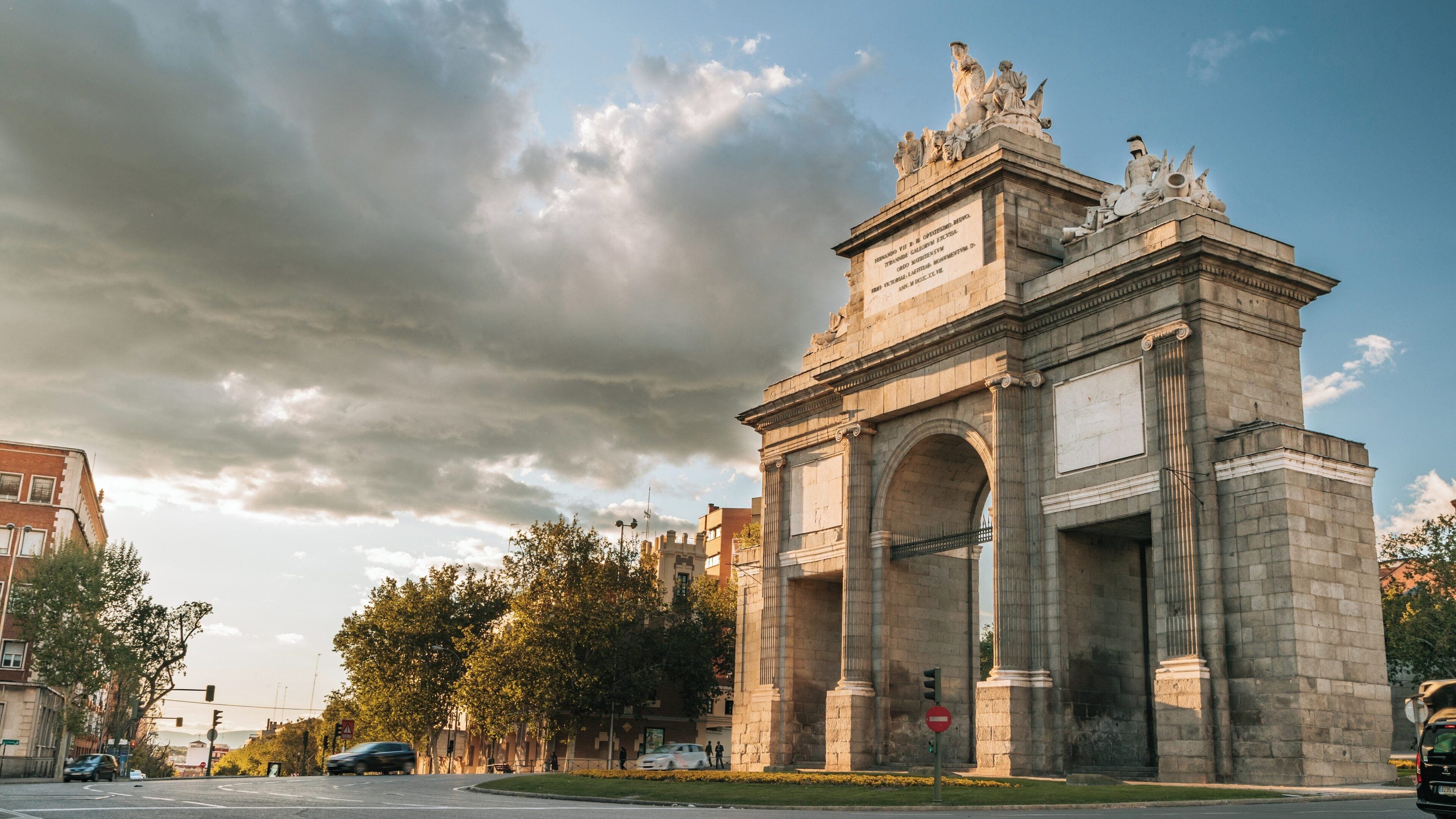 Puerta de Toledo in Arganzuela, Madrid showcases historical architecture under a dramatic sky at sunset
