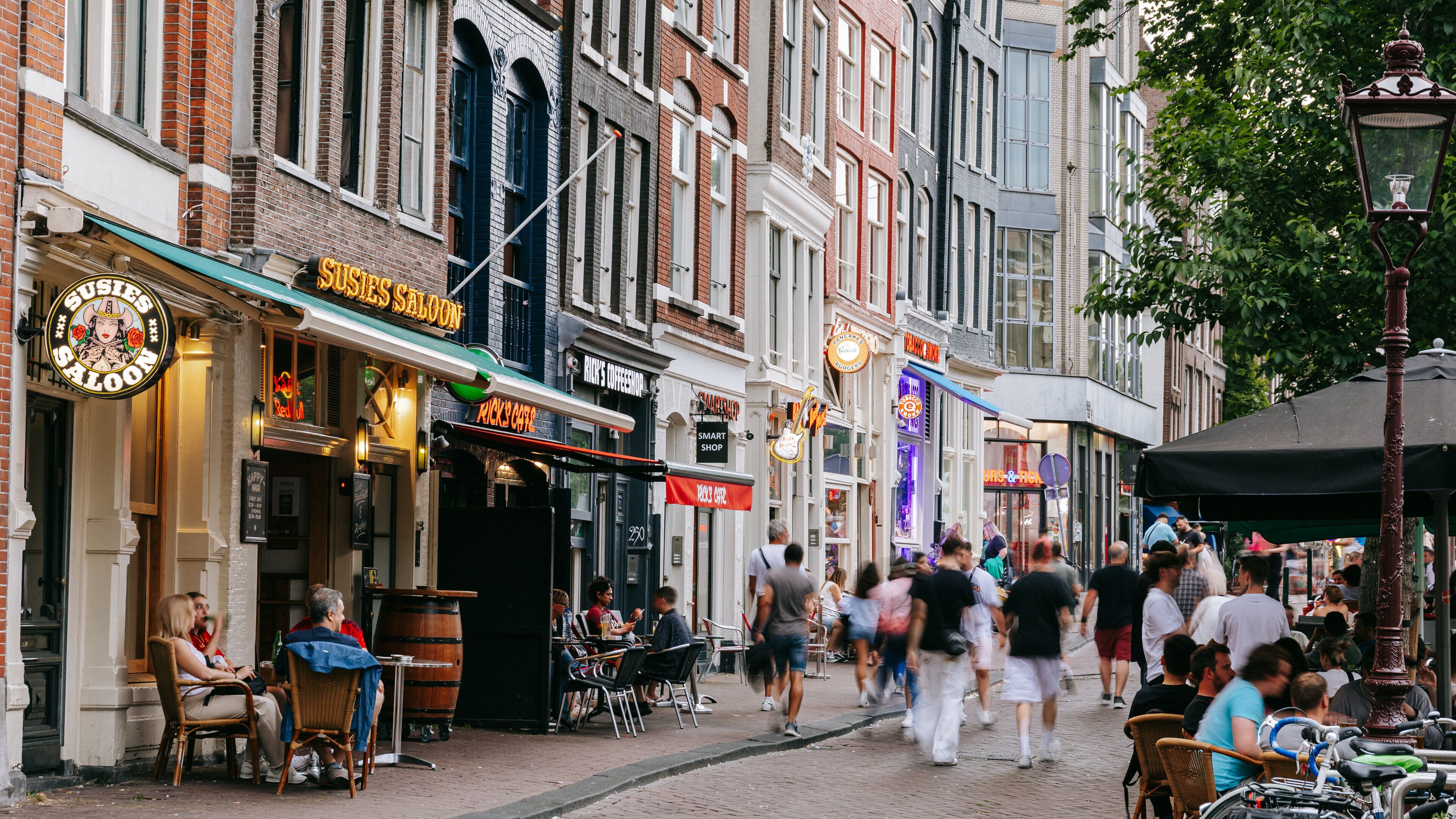 A bustling street with various shops, including a saloon and a coffee shop.
