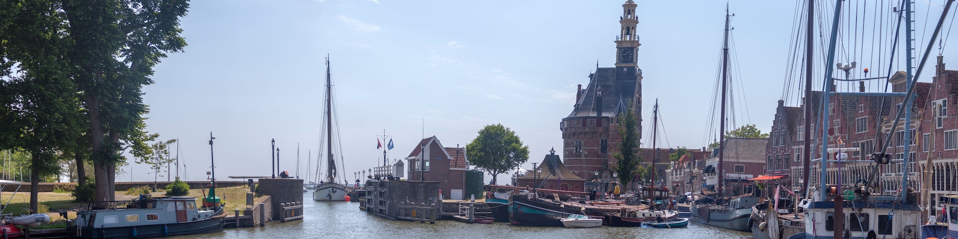 A canal with boats docked, a prominent tower, and historic buildings along the water.