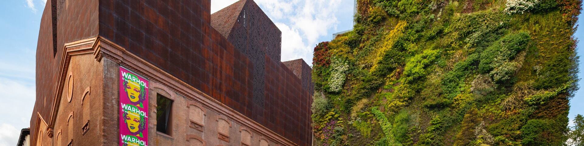 A building with a rust-colored facade and a large billboard featuring Warhol's Marilyn Monroe.
