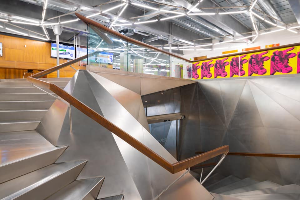 Eine moderne Treppe mit Metallgeländern und einem Schacht für einen Glasaufzug.