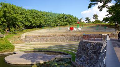 A park with a stone staircase, a pond with lily pads, and a heart-shaped sculpture with the word "MOM" on it.