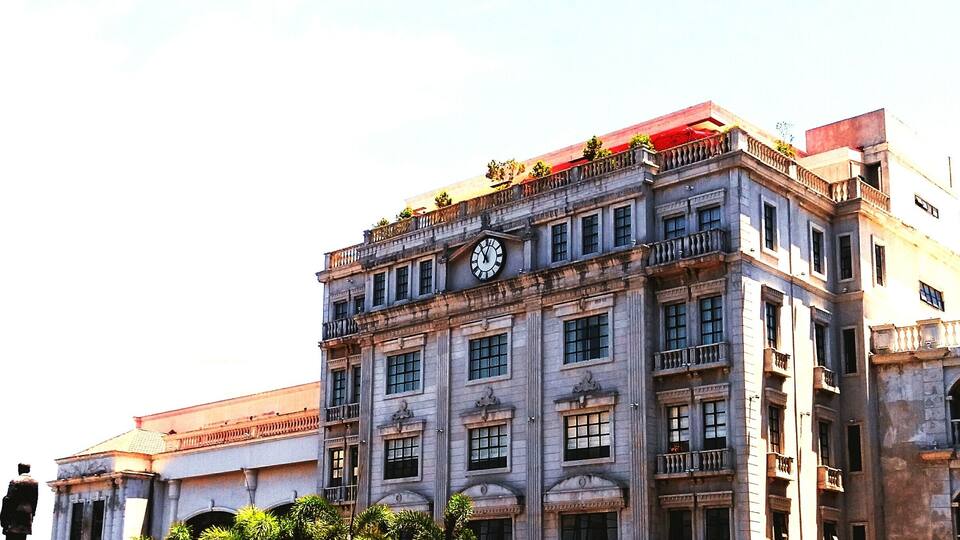 A historic building with a prominent clock tower, ornate balconies, and classical architectural details.