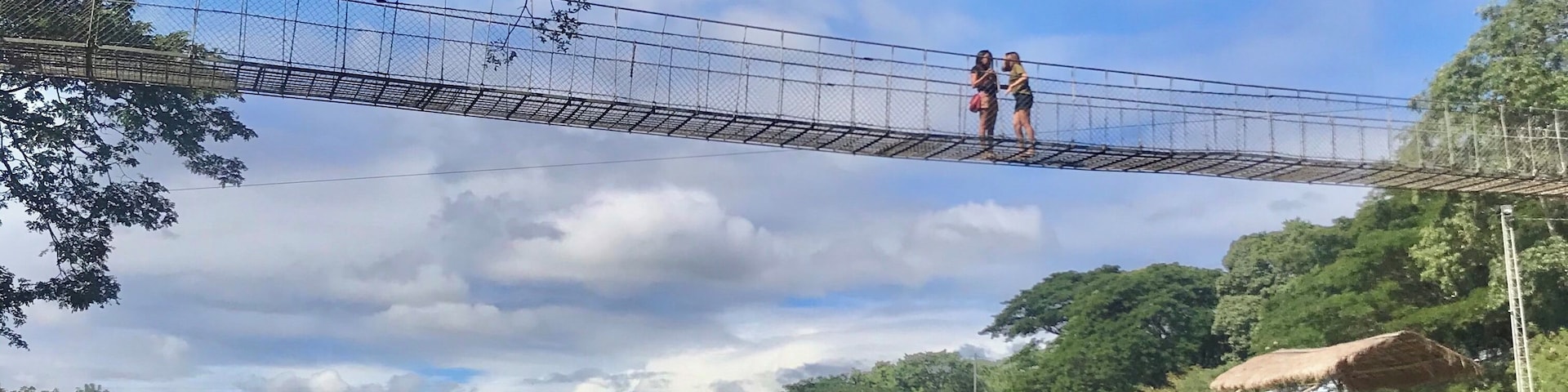 MINALUNGAO NATIONAL PARK
3-4hours drive from Manila 
Unexpected treasure hidden deep 
in the province of General Tinio Nueva Ecija. 
Photo shows 2 locale men manouver the indegenous bamboo Raft full of Excursionist by paddle and another Guy pulling the rope while jumping alongside the rockies and help navigate the River.
Crossing the Penaranda River thru hanging Bridge, Ziplining and walk 1000 steps thru the woods towards the top of the Hills are few activities this place has to offer for a day visit.
Good for outdoor enthusiast.