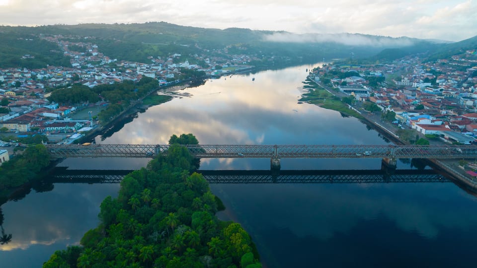 A river with a bridge, surrounded by residential buildings and greenery.