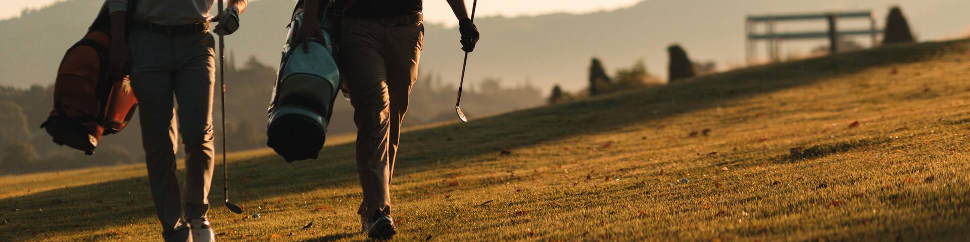silhouette of golfers who walking and carrying golf bags in warm sunshine. leisure and sport concept.