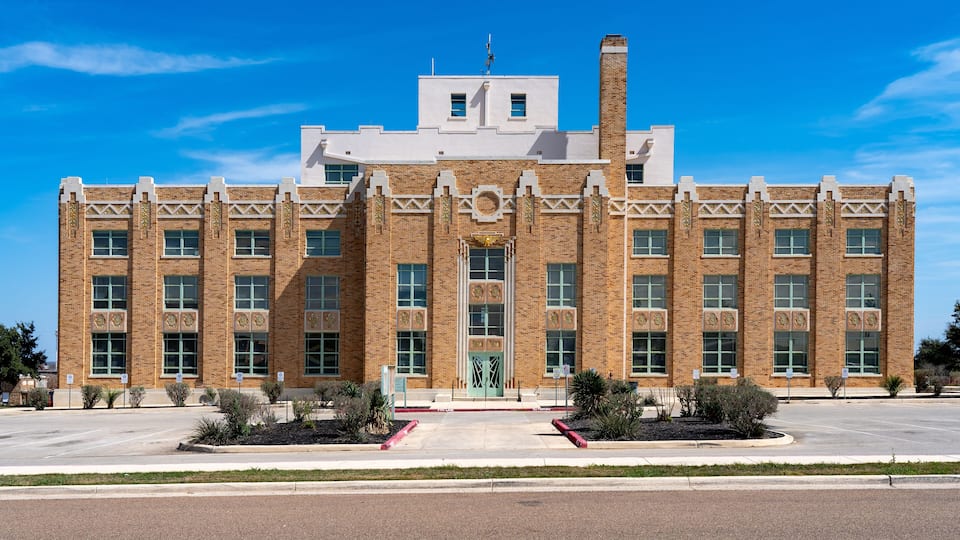 A large brick building with a symmetrical facade, large windows, and a central entrance.