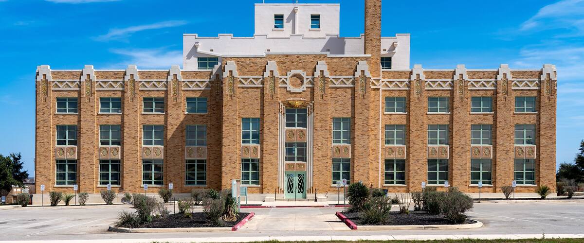 A large brick building with a symmetrical facade, large windows, and a central entrance.