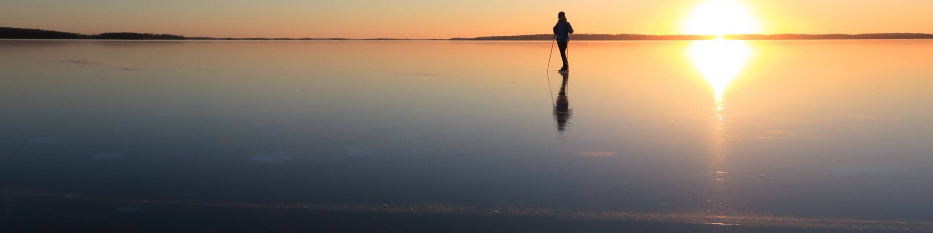 Ice skating on lake Malaren, Sweden, at sunset.