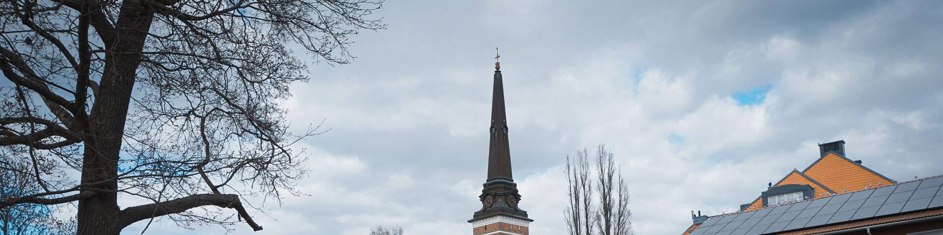 View of buildings by river against cloudy sky