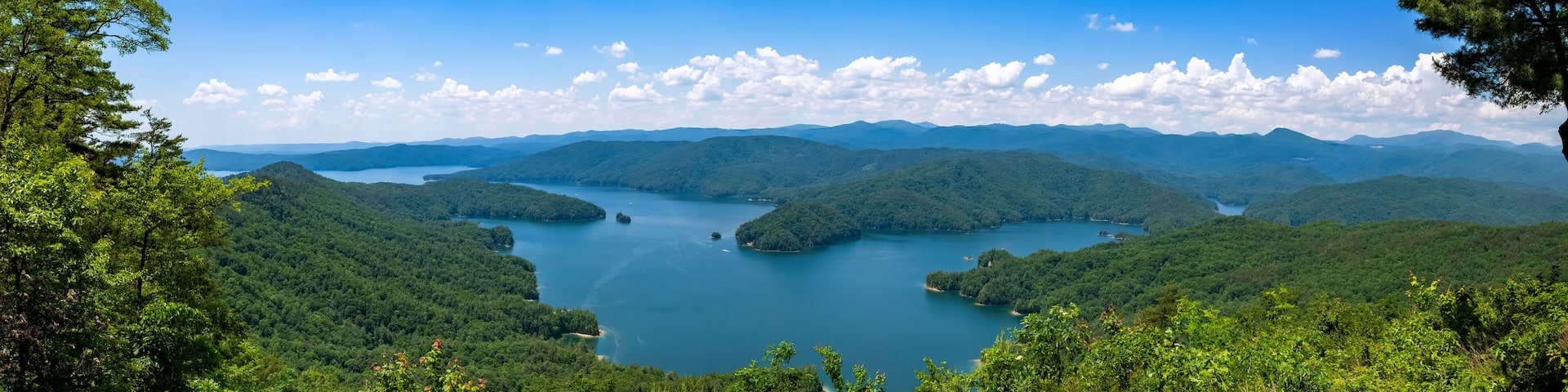 Un lago rodeado de colinas boscosas bajo un cielo azul despejado.