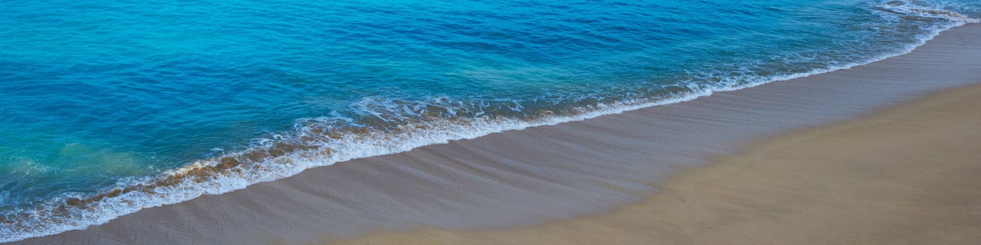 A beach with clear turquoise water and a sandy shore.