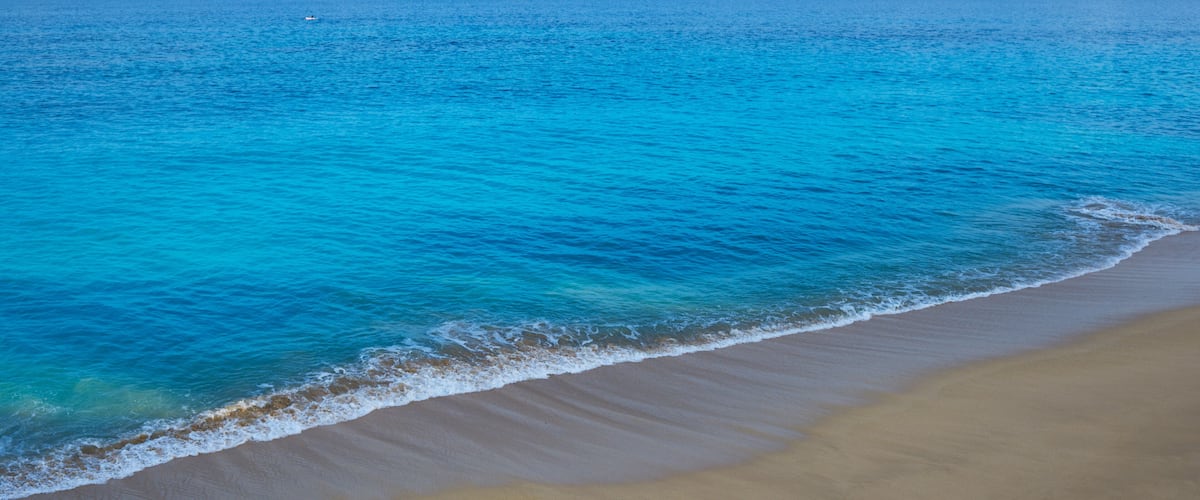 A beach with clear turquoise water and a sandy shore.