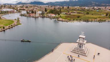 Un río con una barca pequeña, un monumento y un pueblo al fondo.