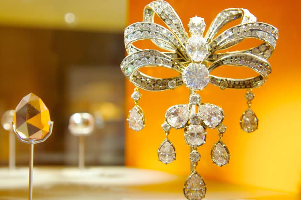 A display of jewelry with a prominent diamond brooch and teardrop-shaped earrings.