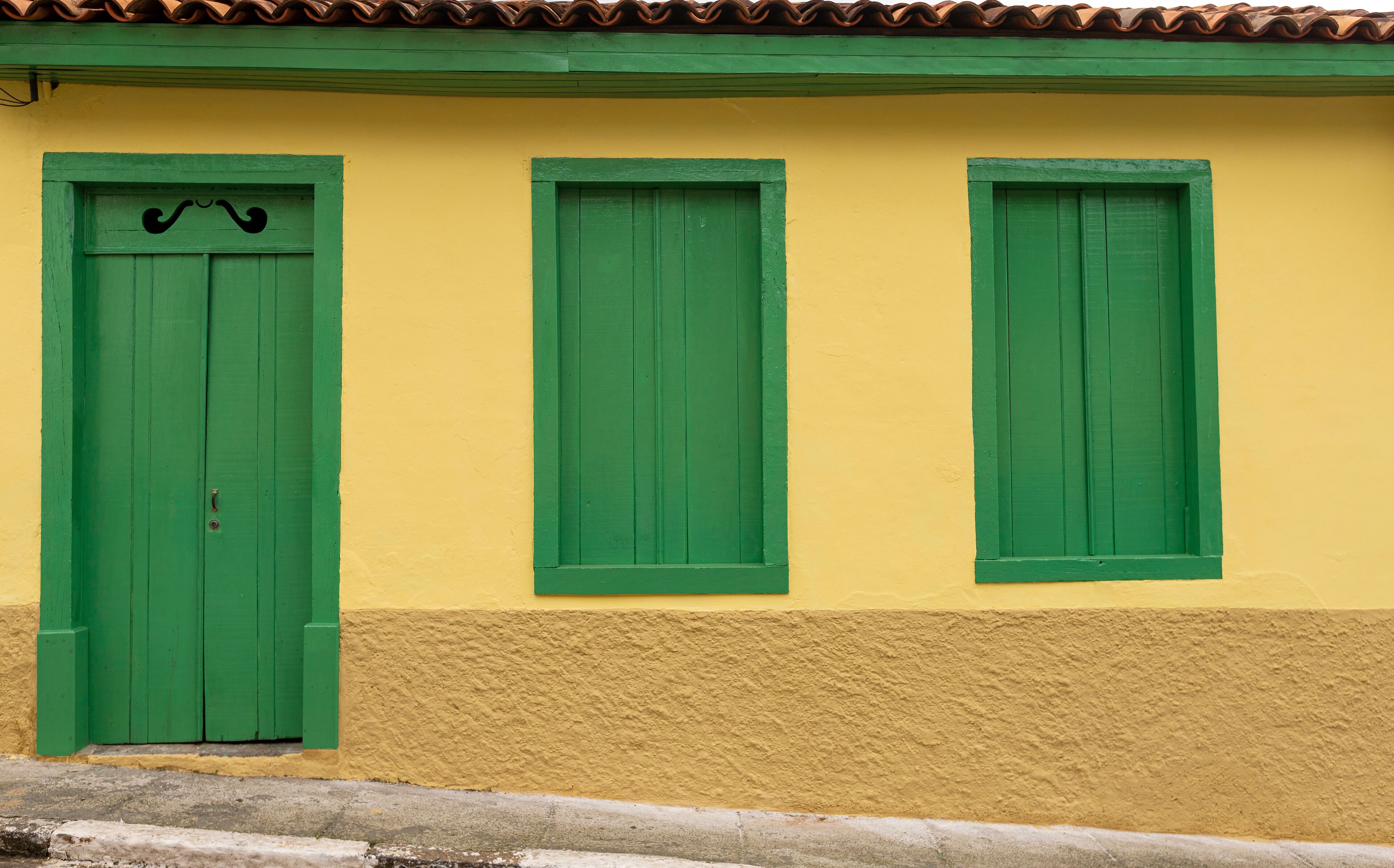 A yellow building with green shutters and a green door.