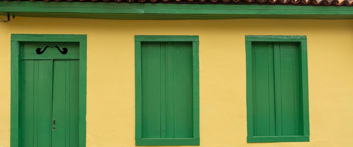 A yellow building with green shutters and a green door.