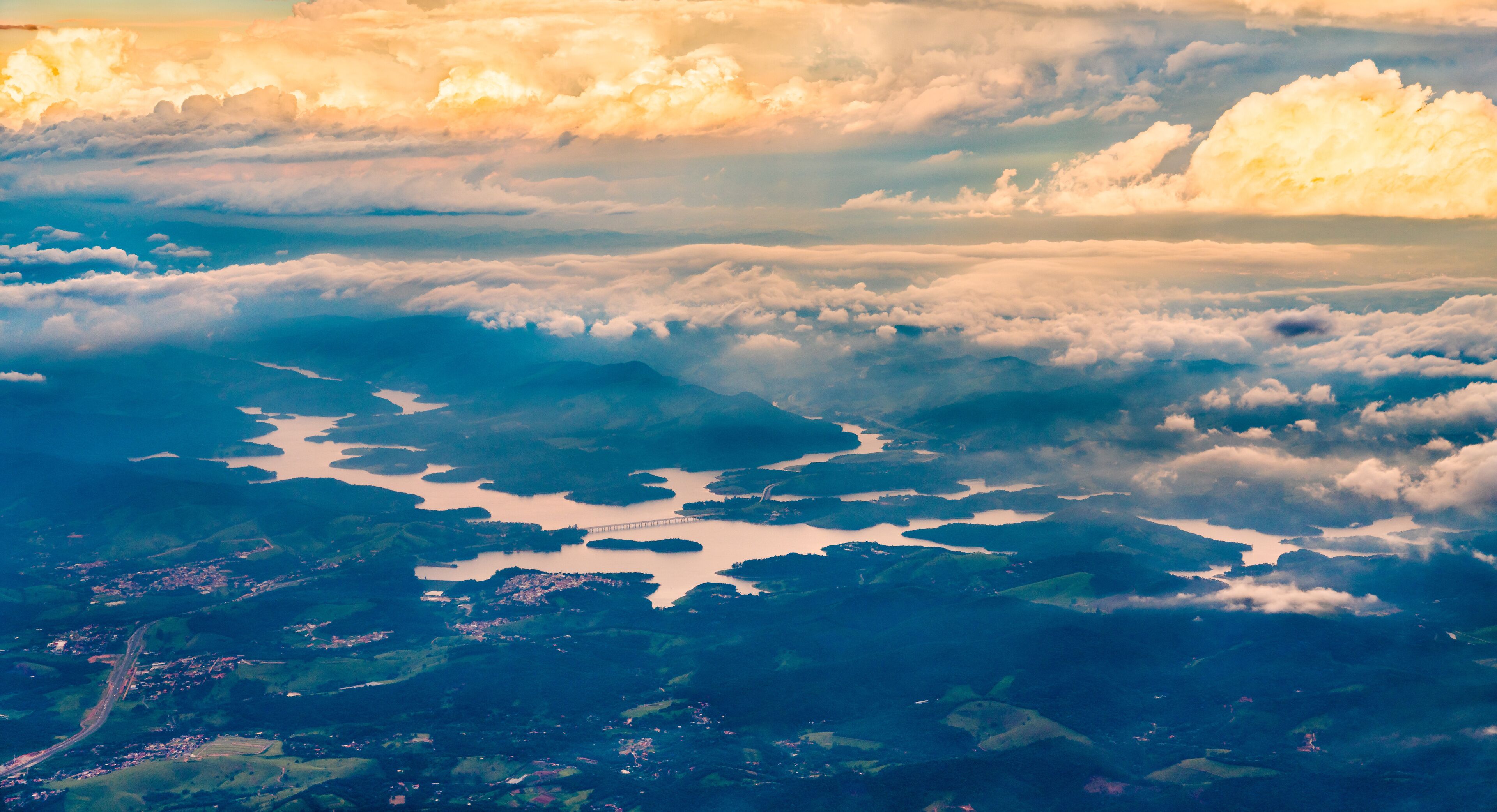 A landscape with a river, bridges, and a cloudy sky.