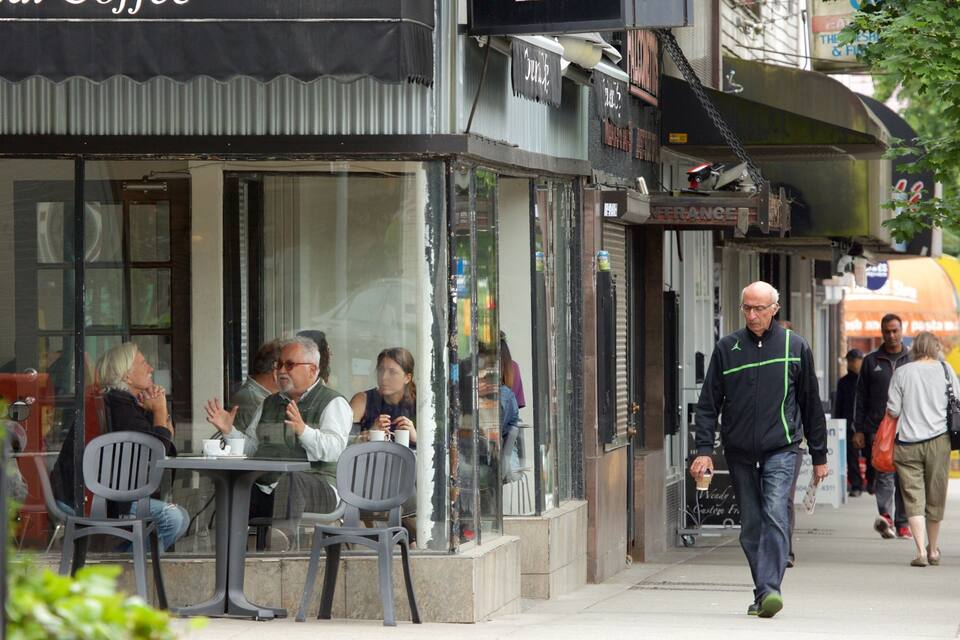 A café with outdoor seating, people sitting and walking by.