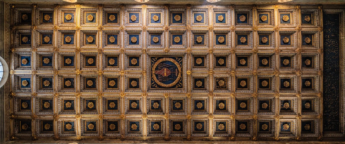 A ceiling with intricate golden patterns and a central circular design.