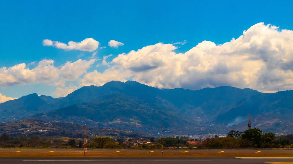 A mountainous landscape with a clear sky and a runway in the foreground.