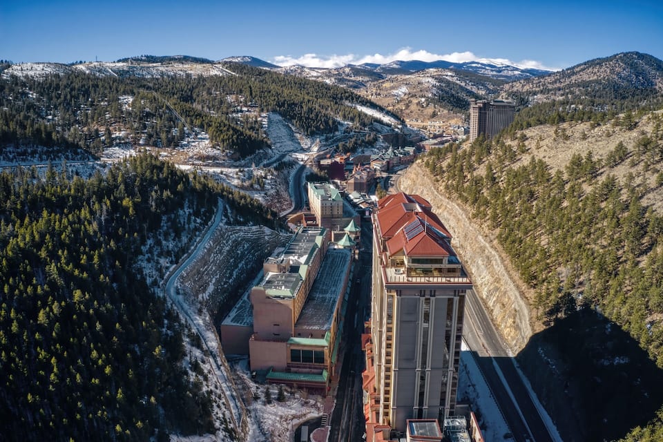 Paesaggio montuoso con una cittadina situata in una valle, caratterizzato da un edificio con tetto rosso e un'alta torre.