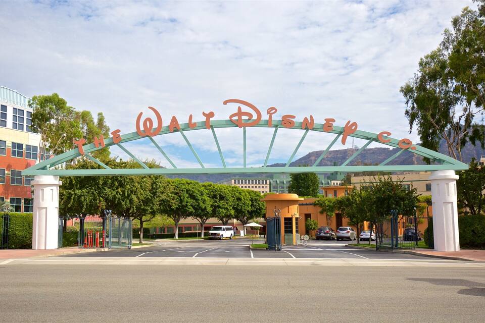 The entrance to Walt Disney World with a large arch sign, trees, and buildings in the background.