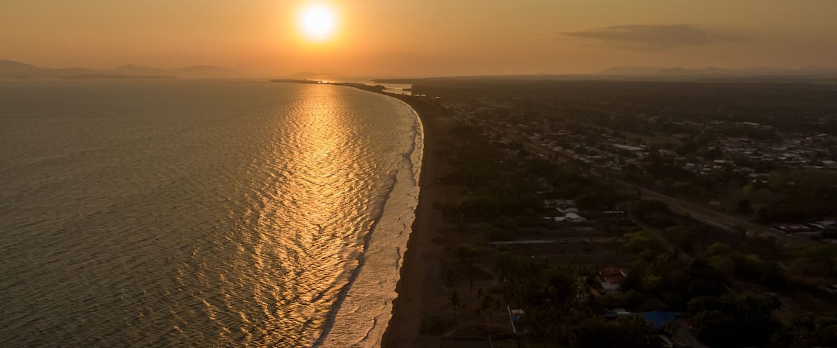 A coastal sunset with a beach and a town in the background.