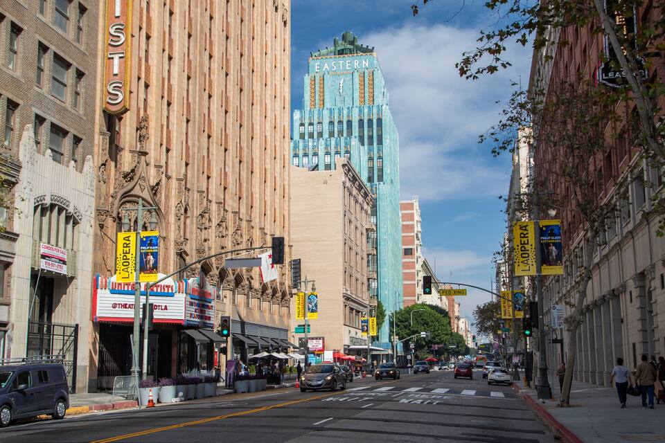 A city street lined with historic buildings, including a theater and a building with 'EASTERN' on its facade.