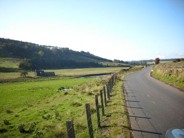 The B6355 heading for the moors. The road running near the river, a derelict cottage sits forlorn over the river.
