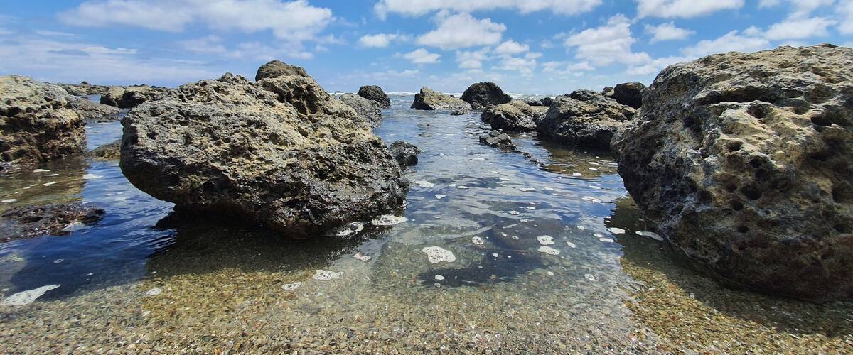A rocky shoreline with clear water and pebbles.