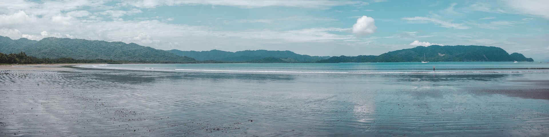 Tide out on the empty Bahia Ballena with no people on a sunny day near Montezuma, on the Pacific coast of Costa Rica