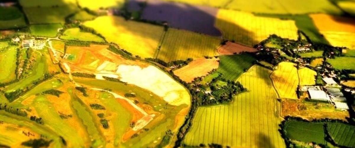 A close-up of a patchwork of fields with varying colors and patterns, indicating different crops or stages of growth.