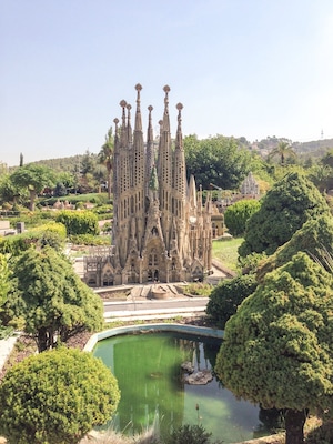 A Gothic-style cathedral with intricate spires, surrounded by lush greenery and a small pond.