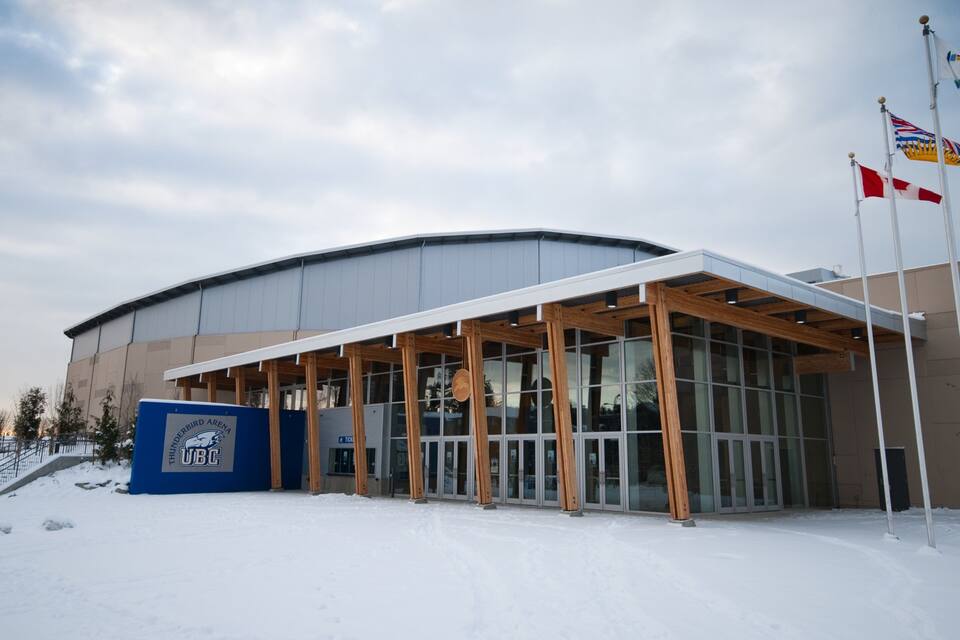 A modern building with a curved roof and large glass windows, surrounded by snow.
