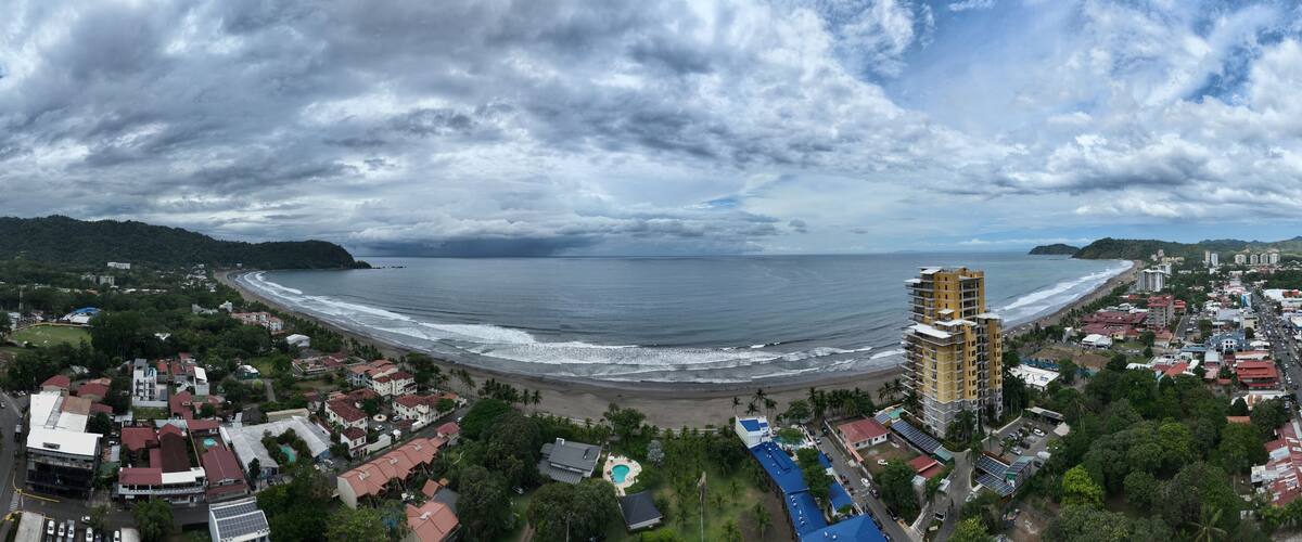 A coastal cityscape with a beach, ocean, and a tall building.